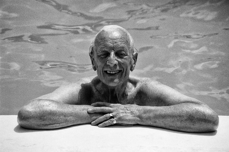 Elderly man in a swimming pool leaning on the edge, smiling