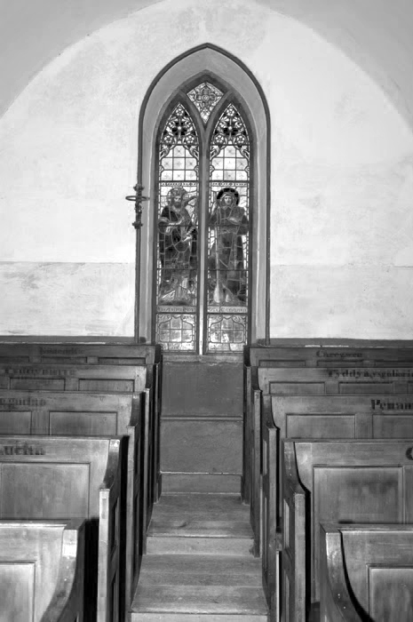 Interior of Ynyscynhaearn church showing the wooden pews and stained glass window