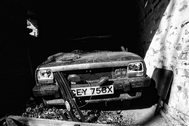 The wreck of an old car in a derelict garage, photographed from the front