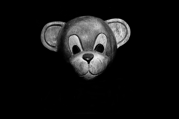 face of a toy monkey staring ahead surrounded by negative black space