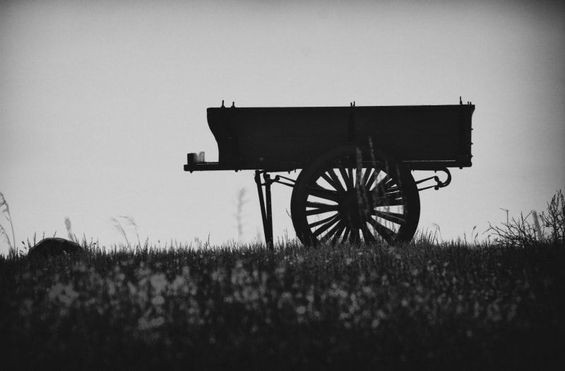 Silhouette of a wooden cart on a grassy hillside