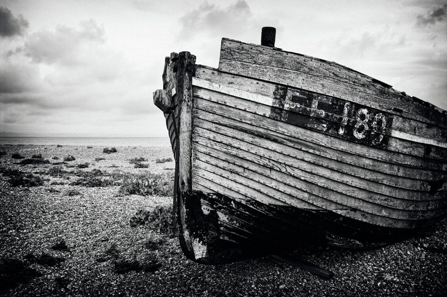 The bow of a decaying fishing boat sitting on the shingle beach at Dungeness