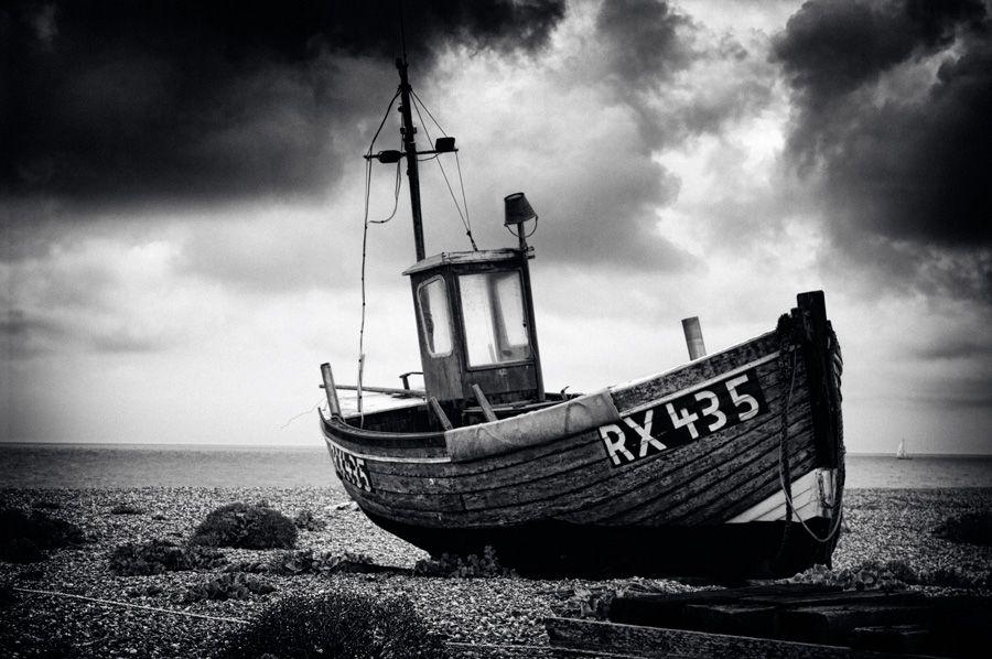 An abandoned fishing boat under a menacing sky at Dungeness