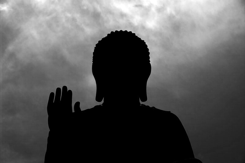 Silhouette of Buddha's head and raised hand, facing toward the camera