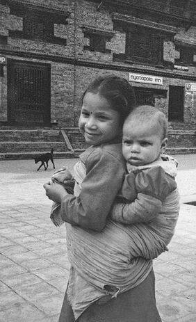 A young girl carries a baby on her back in a small town in Nepal