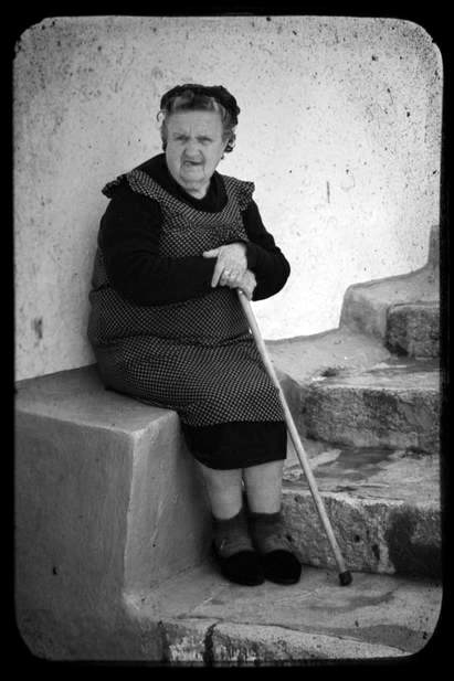 Elderly lady with walking stick sitting on a step