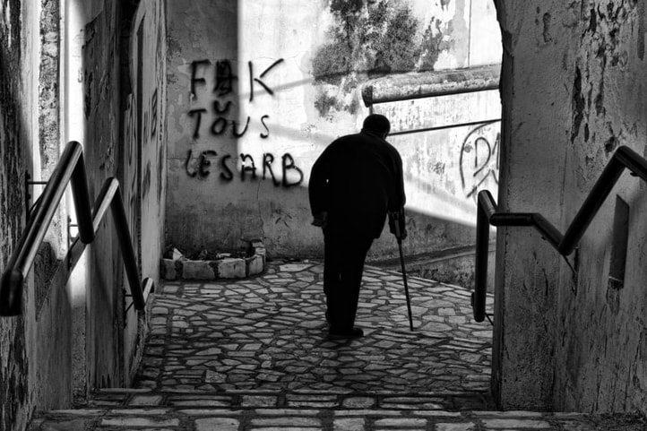 Silhouette of a disabled man walking down a flight of stairs alongside graffiti supporting the Jasmine Revolution in Tunisia
