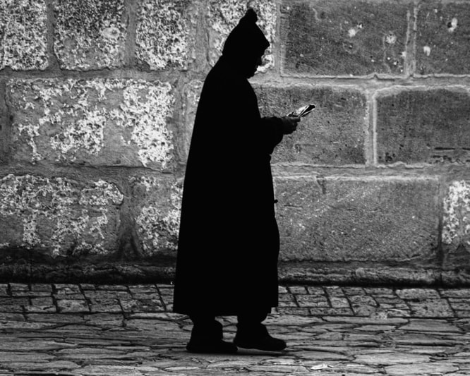 tun0010bw10x8p_2 Silhouette of a man in a djellabah walking along reading a newspaper in Tunisia