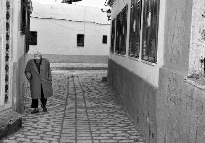 An old man with a walking stick in the narrow streets of a medina in Tunisia