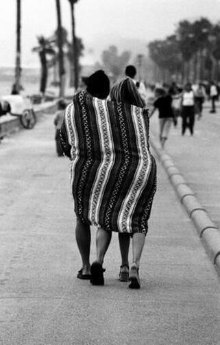 Couple covered in a striped blanket walking in harmony away from the camera